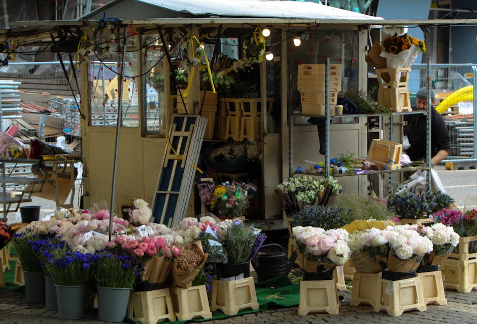 A flower stall in Putney markets displaying a variety of fresh floral arrangements and bouquets, including pink, white, purple, and blue flowers such as peonies, carnations, and lavender, arranged in